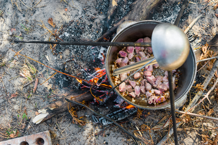 meat stewing in kettle on campfire outside