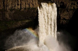 A photograph of a massive waterfall cascading down a huge rock outcrop with a kayaker just about to take the plunge