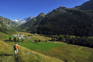 photograph of mountain valley on a sunny day with lone trekker walking into the distance