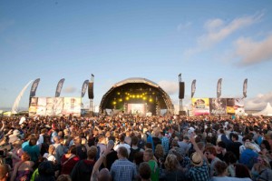photograph of a large crowd and music stage under a blue sky